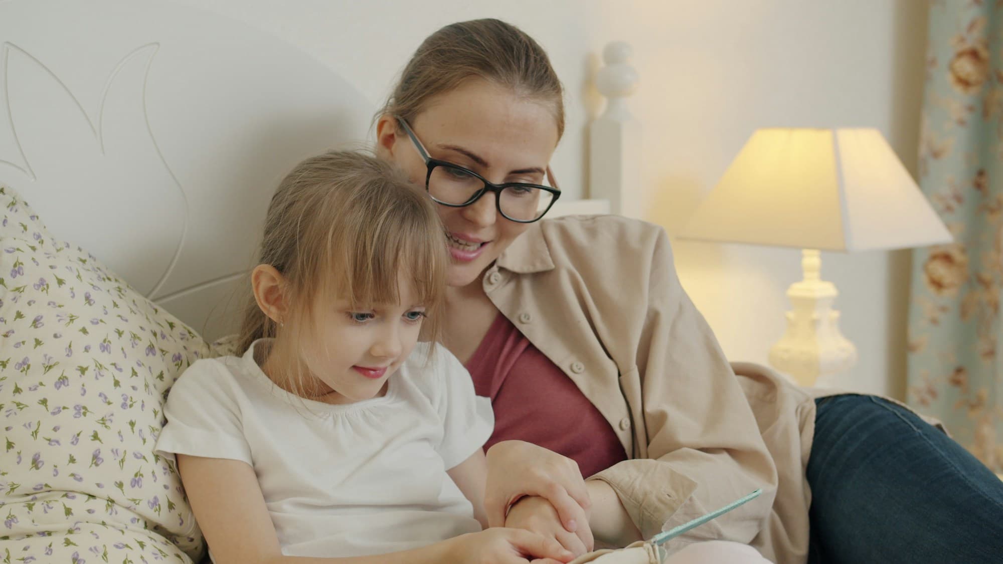 A parent reading a bedtime story to a child by lamplight